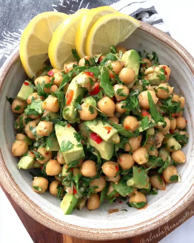 Flat lay of chickpea avocado salad ingredients including avocado, red bell pepper, chickpeas, cilantro, and lime.