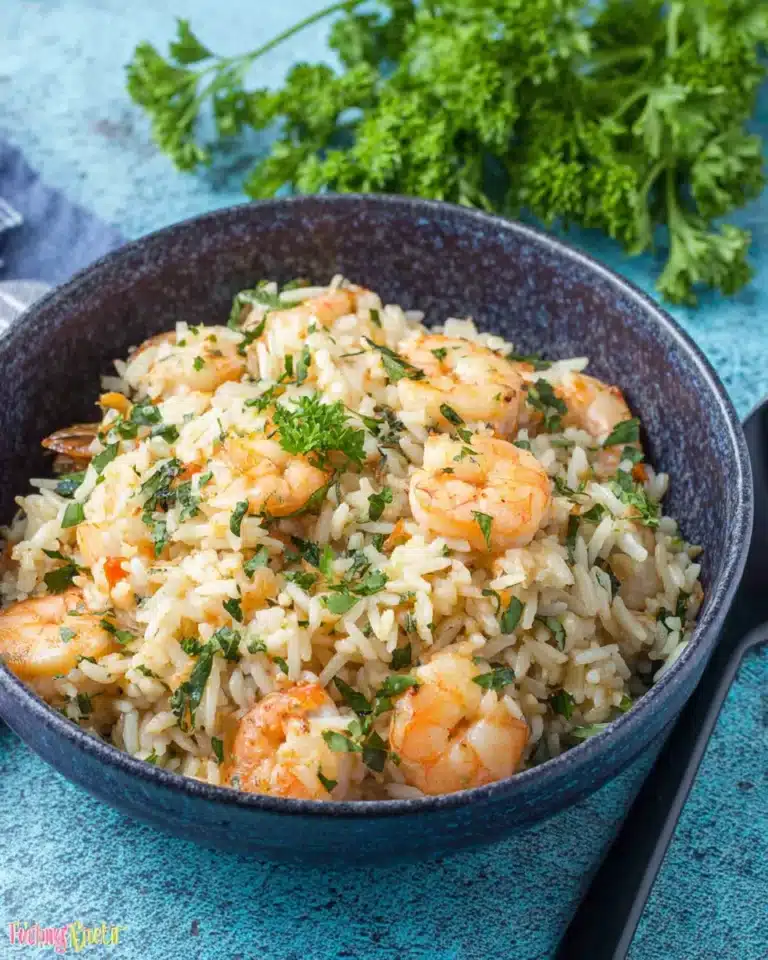 Garlic butter shrimp and rice served in a blue ceramic bowl, topped with fresh parsley, showing fluffy rice and tender shrimp.