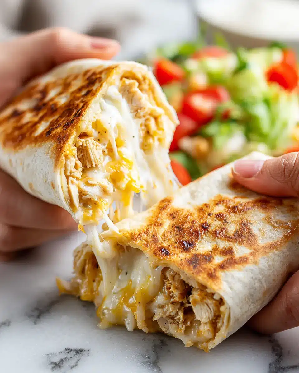 Cheesy Garlic Chicken Wrap Close-Up Hand holding cheesy garlic chicken wrap with melted cheese and chicken filling.