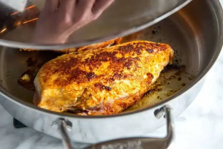 Simple juicy chicken dinner with chicken breast cooking covered in a skillet